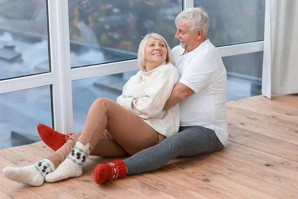 Feliz casal maduro sentado no chão perto da janela em casa — Fotografia de Stock