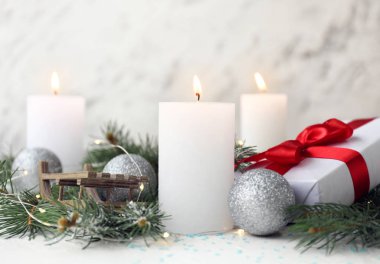 Noel dekorlu parlak mumlar ve beyaz arka planda hediye.