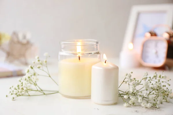 Glowing candles with flowers on white table — Stock Photo, Image
