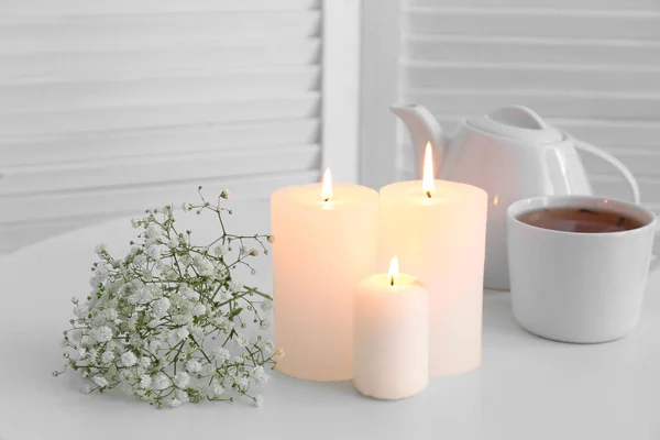 Glowing candles with tea and flowers on table — Stock Photo, Image