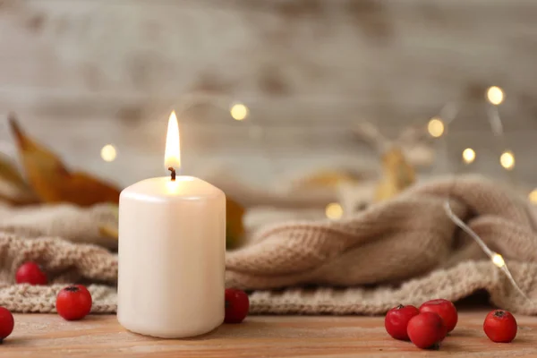 Glowing candle with berries and plaid on wooden table — ストック写真