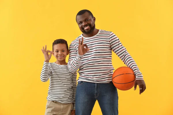 Retrato de homem afro-americano e seu filho com bola mostrando OK no fundo de cor — Fotografia de Stock