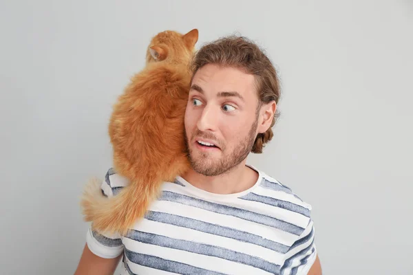 Uomo con simpatico gatto su sfondo chiaro — Foto Stock