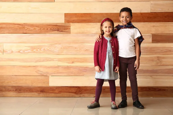 Niños pequeños de moda en ropa de otoño cerca de la pared de madera — Foto de Stock