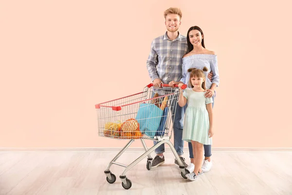 Familia con carrito de compras cerca de la pared de color —  Fotos de Stock