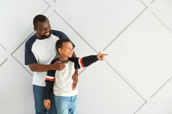 Portret Afroamerykanina ze swoim synkiem wskazującym na coś na jasnym tle — Zdjęcie stockowe