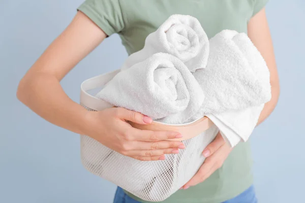 Woman holding basket with clean towels on color background — ストック写真