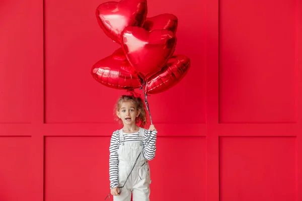 Schattig klein meisje met luchtballonnen op een kleurrijke achtergrond. Valentijnsdag — Stockfoto