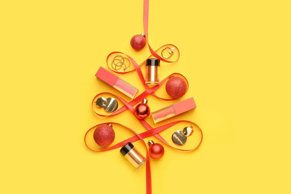 Bellissimo albero di Natale fatto di cosmetici per il trucco, gioielli e nastro su sfondo colore — Foto Stock