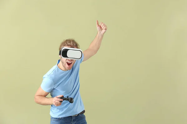 Giovane uomo con occhiali VR e pad gioco su sfondo a colori — Foto Stock