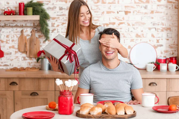 Mutlu genç bir kadın Noel hediyesini evde erkek arkadaşına veriyor.