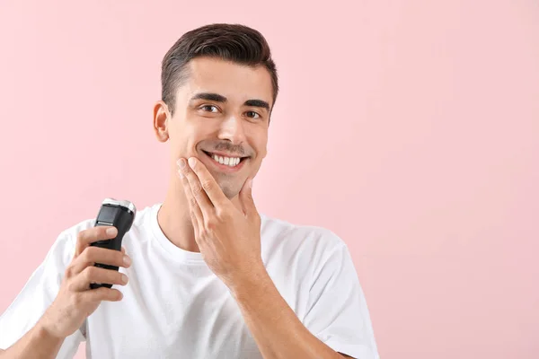 Schöner junger Mann rasiert sich auf farbigem Hintergrund — Stockfoto