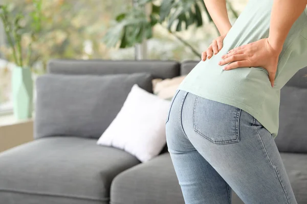 Young woman suffering from back pain at home — Stock Photo, Image