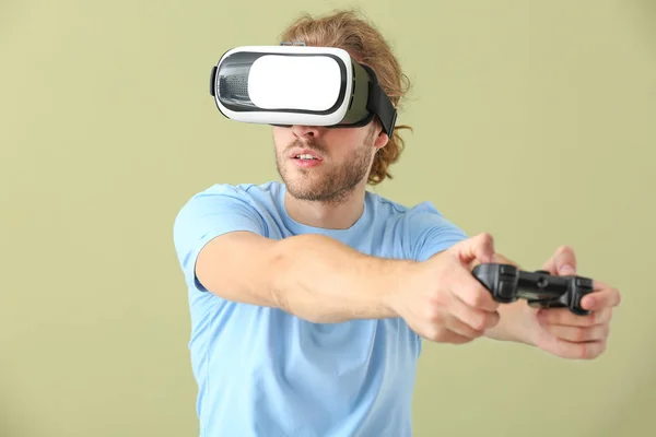 Hombre joven con gafas VR y almohadilla de juego sobre fondo de color —  Fotos de Stock