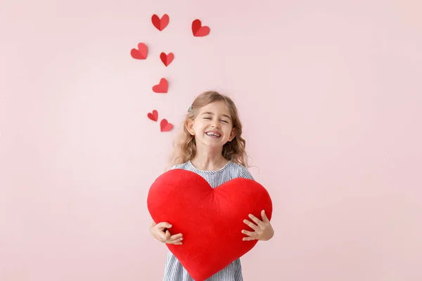 Ragazzina carina con cuscino a forma di cuore su sfondo a colori. Festa di San Valentino — Foto Stock