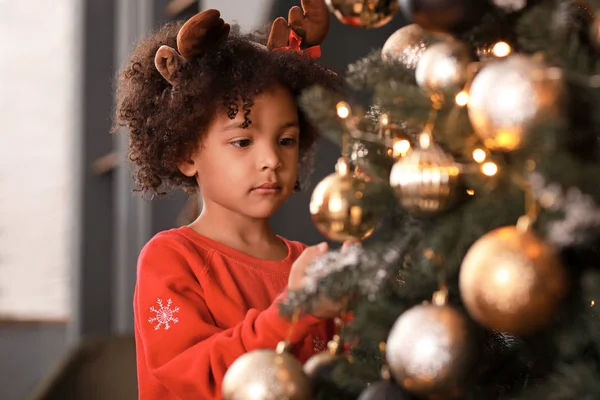 Little African-American girl decorating Christmas tree at home — Stock Photo, Image