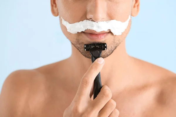 Schöner junger Mann rasiert sich auf farbigem Hintergrund, Nahaufnahme — Stockfoto