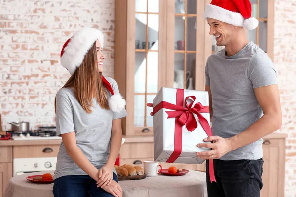 Jovem feliz dando presente de Natal para sua namorada em casa — Fotografia de Stock