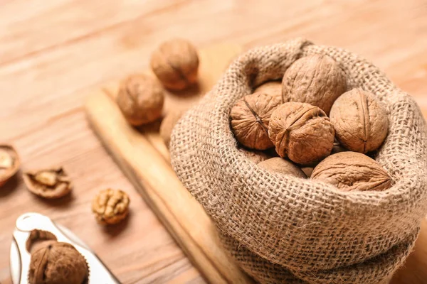 Sack with tasty walnuts on wooden background — Stock Photo, Image