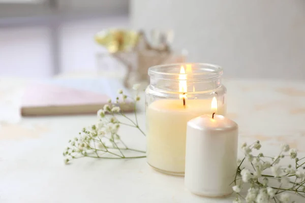 Velas brillantes con flores sobre mesa blanca — Foto de Stock