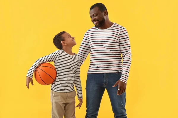 Portrait of African-American man and his little son with ball on color background — Stok Foto