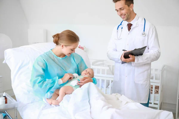 Jonge vrouw met pasgeboren baby en gynaecoloog in kraamkliniek — Stockfoto