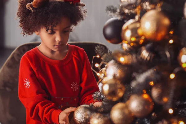 Little African-American girl decorating Christmas tree at home — Stock Photo, Image