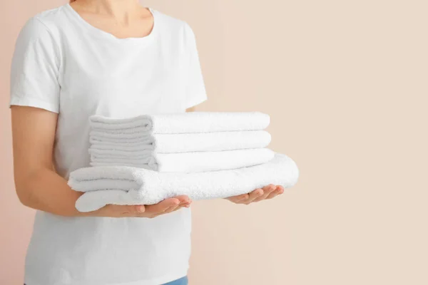 Kobieta z czystymi ręcznikami na tle koloru — Zdjęcie stockowe