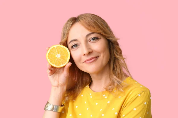 Stylish mature woman with orange on color background — Stock Photo, Image