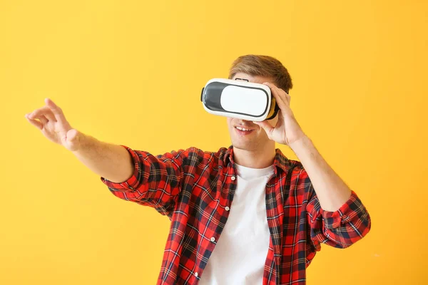 Young man with virtual reality glasses on color background — Stock Photo, Image