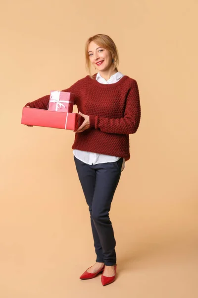 Belle femme mature avec des boîtes-cadeaux sur fond de couleur — Photo