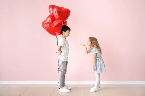 Little girl sending kiss for cute boy with air balloons on color background. Valentines Day celebration — Stock Photo, Image