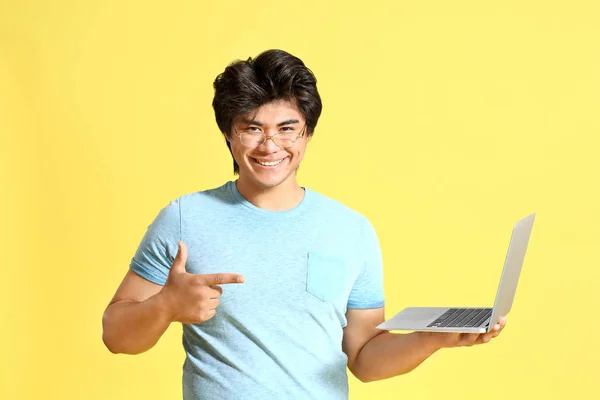 Male Asian programmer with laptop on color background — Stock Photo, Image