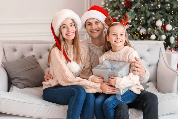 Happy young family with Christmas gift at home — Stock Photo, Image