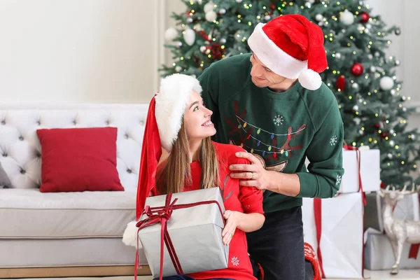 Jovem casal feliz com presente de Natal em casa — Fotografia de Stock