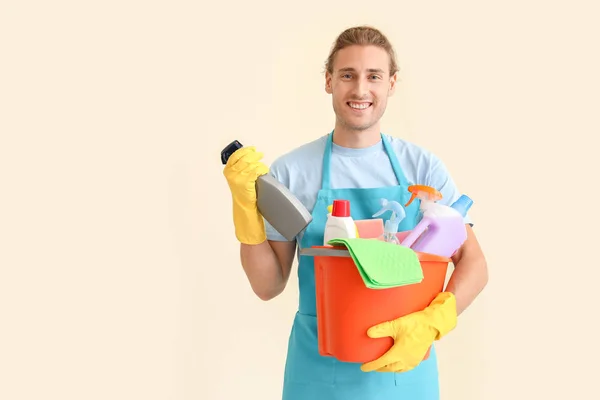 Male janitor with cleaning supplies on light background — Stock Photo, Image