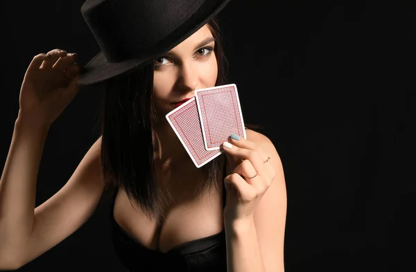 Krásná mladá žena s hracími kartami na tmavém pozadí — Stock fotografie