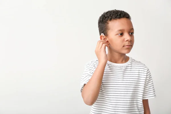 Pequeño niño afroamericano con audífono sobre fondo claro — Foto de Stock