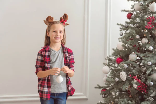 Glückliches kleines Mädchen schmückt Weihnachtsbaum zu Hause — Stockfoto