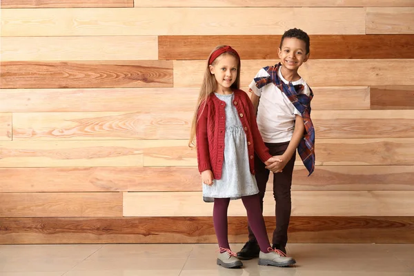 Fashionable little children in autumn clothes near wooden wall — Stock Photo, Image