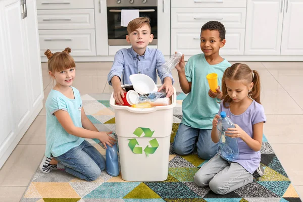 Małe dzieci i pojemnik ze śmieciami w kuchni. Pojęcie recyklingu — Zdjęcie stockowe