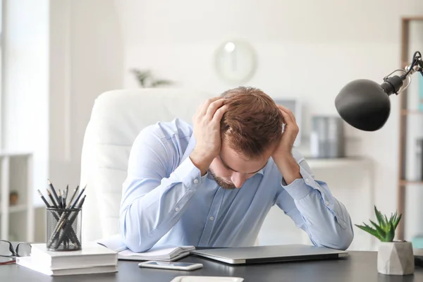 Young man suffering from headache in office — Stock Photo, Image