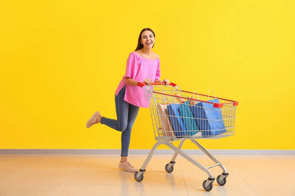 Jonge vrouw met wagentje in de buurt van kleur muur — Stockfoto