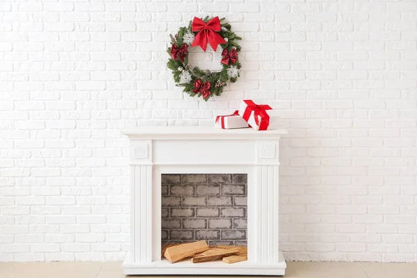 Beautiful Christmas wreath hanging on wall near fireplace with gift boxes — Stock Photo, Image