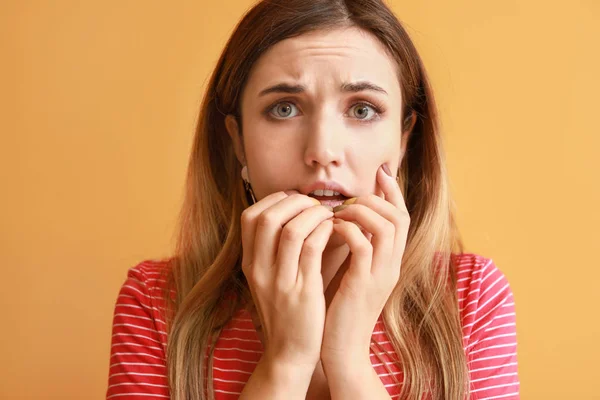 Portrait of worried young woman on color background — Stock Photo, Image