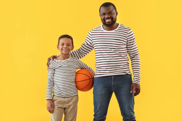 Portrait of African-American man and his little son with ball on color background — Stok Foto