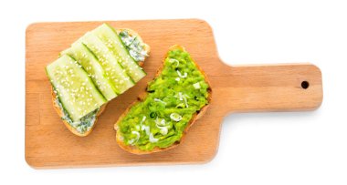 Beyaz arka planda lezzetli avokado sandviçleri olan tahta