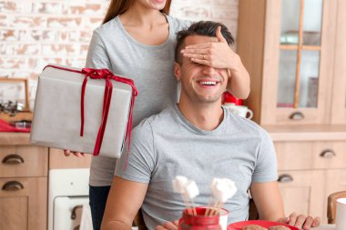Mutlu genç bir kadın Noel hediyesini evde erkek arkadaşına veriyor.