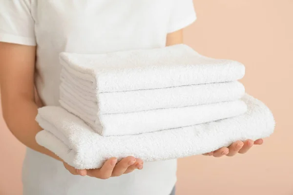 Kobieta z czystymi ręcznikami na tle koloru, zbliżenie — Zdjęcie stockowe