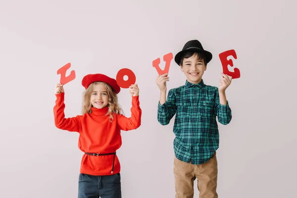 Söta små barn med ord Kärlek på grå bakgrund. Alla hjärtans dag firande — Stockfoto